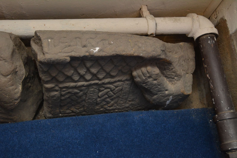 One of two broken fragments of hogbacks wedged against the northern wall of the nave, in between a small altar and the heating pipes.
