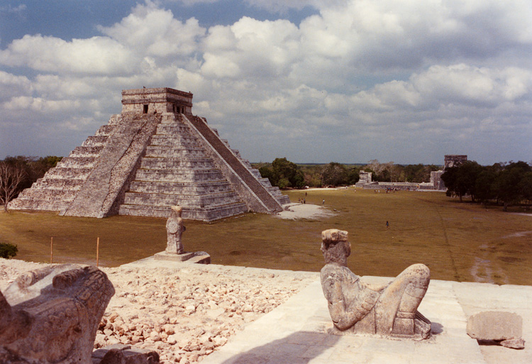A view of El Castillo taken from The Temple of the Warriors with the reclining statue of the god Chac in the foreground and a serpents head on the left. It is said that the Mayan priests used the statue to cut out the hearts of living victims in order to ensure the rising of the sun every day. (This photo taken in 1994 cannot be taken by the public anymore, as I gather the Temple of the Warriors i