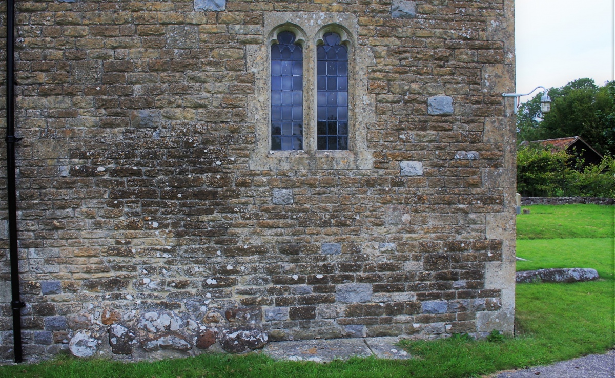 Near the SE corner of the church (see the sarsen-type stone lying to the right), the footings of the church are quite different in construction from the rest, except for a similar stretch near to the NW corner. One might be forgiven for considering that the church had been built partly, or entirely, on top of an older, simpler structure.