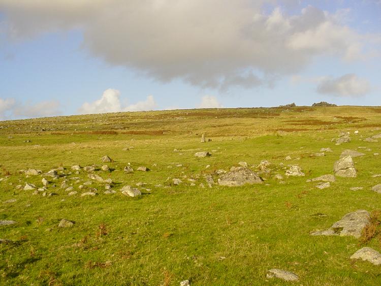 Trowlesworthy E Cairn. A close shot of the Cairn. The last stone of the Trowlesworthy W Stone Row can be seen just over the center of the cairn, while the center barrow is just to the right of the stone. The right barrow of the formation can be semi-identified to the center-left of the picture.