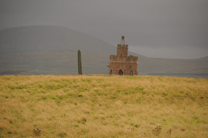 Hurl Stone The Hurl Stone is the sharp 'needle' to the left of the modern tower, which was built by the landowner in 2000. As there are no public footpaths to the stone, I have written to ask for permission to walk across the field to take close up photographs.