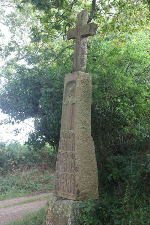 Croix des Douze Apotres at Rungleo.

This view is taken from the west side of the menhir. The height of the menhir must be about 3 metres to the top of the cross. Possibly stone with cross is about 2.2 metres. It is diccifult to judge because the roadway is sunk below the level of the base of the menhir.