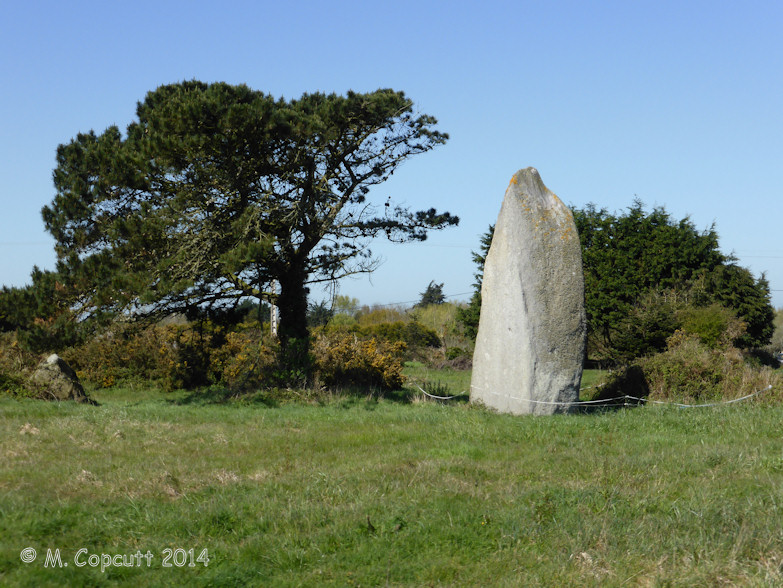 Absolutely splendid menhir which is easily found near to a corner in a little open farmland lane, just behind a little scrubland area. 

The locality of the stone is a bit marshy, and perhaps there is a spring nearby, underneath some of the wooded glades.

Not far away to the east (~20 metres) is another large stone, which looks fairly natural, but I have no doubt it has some relation to the m