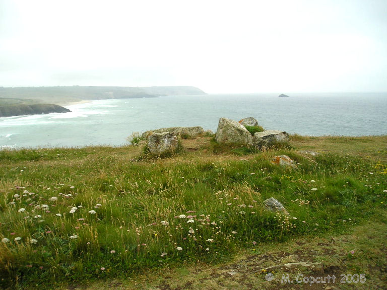 On the headland there is what appears to be the remains of some sort of cairn and burial chamber on the top. It wouldn't be unusual for one to be in such a place. 
There are 6 stones still sticking out of the ground here, and stumps of others to be seen, which sort of make a rectangle inside a circular cairn. 