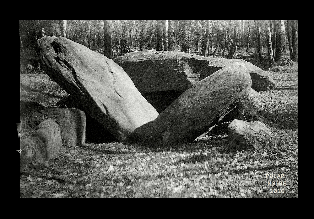 Damaged by blasting attempts, but still an impressive site. Seen from the West in March 2016. The chamber and its covering barrow are remarkably well preserved in the East while the Western end has been damaged. The central capstone broke as a result of a blasting attempt in the early 20th century. Photo taken with Ihagee Paff Reflex camera from 1921 on Ilford Delta 400 film.  