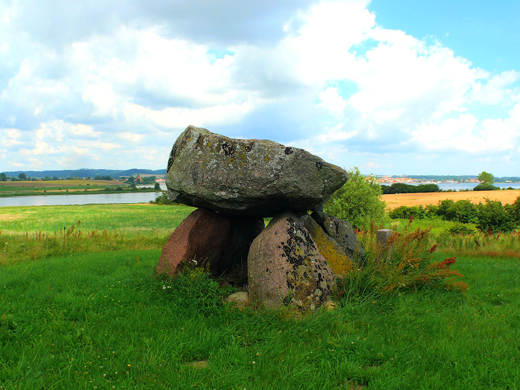 Runddysse (Burial Chamber) near Faaborg (Fyn)

Dolmen, free-standing, oriented E-W.
Set with two carrying stones in N and also two in S;
one smaller stone seen in the east, a threshold stone.
Carrying stones missing in the W-end, where the chamber is thus completely
exposed.
On the big capstone a few cupmarks and a series of split grooves.
Inner chamber preserved size: 2.5 x 1.3 m., height