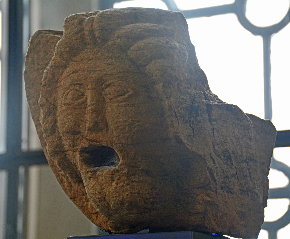 Museum accession no. GLAHM:138045, this fountainhead was difficult (for me) to photograph with the light from the large windows above and behind this sculpture were creating halos, even with a UV filter.  Found at the luxurious bath-house at Bearsden Roman Fort, East Dunbartonshire, the bath-house is recorded as part of Canmore 44532. The museum information sign says Roman sculpture on the Antonin